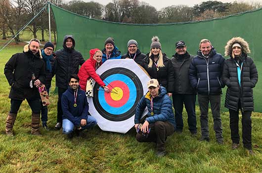 Group of people standing together with an archery target